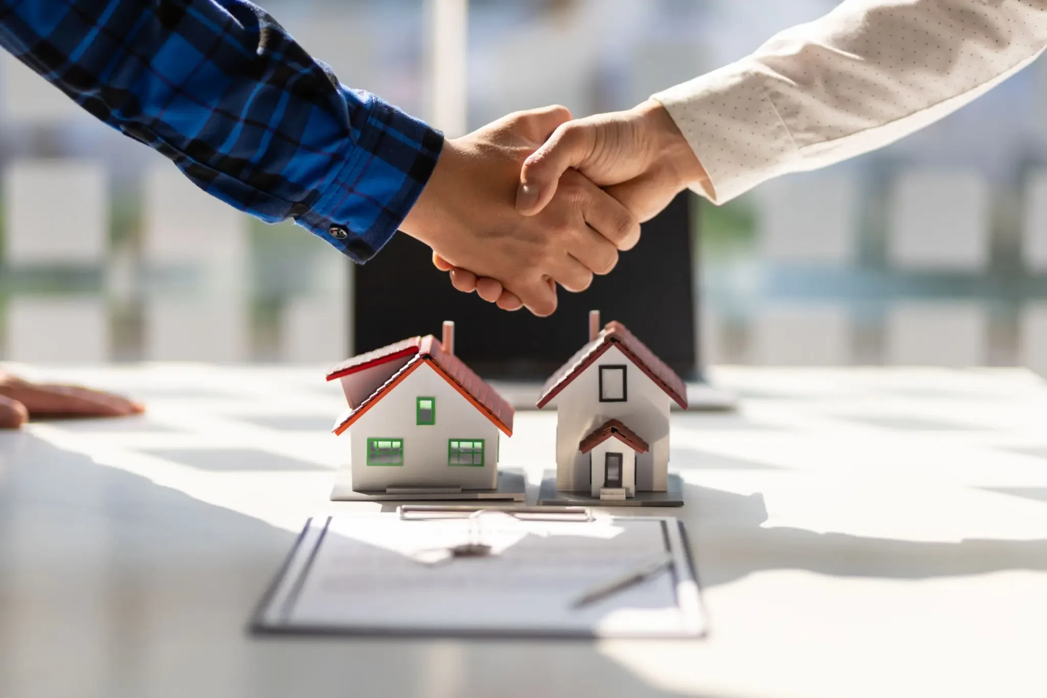 Real estate transaction handshake over house models